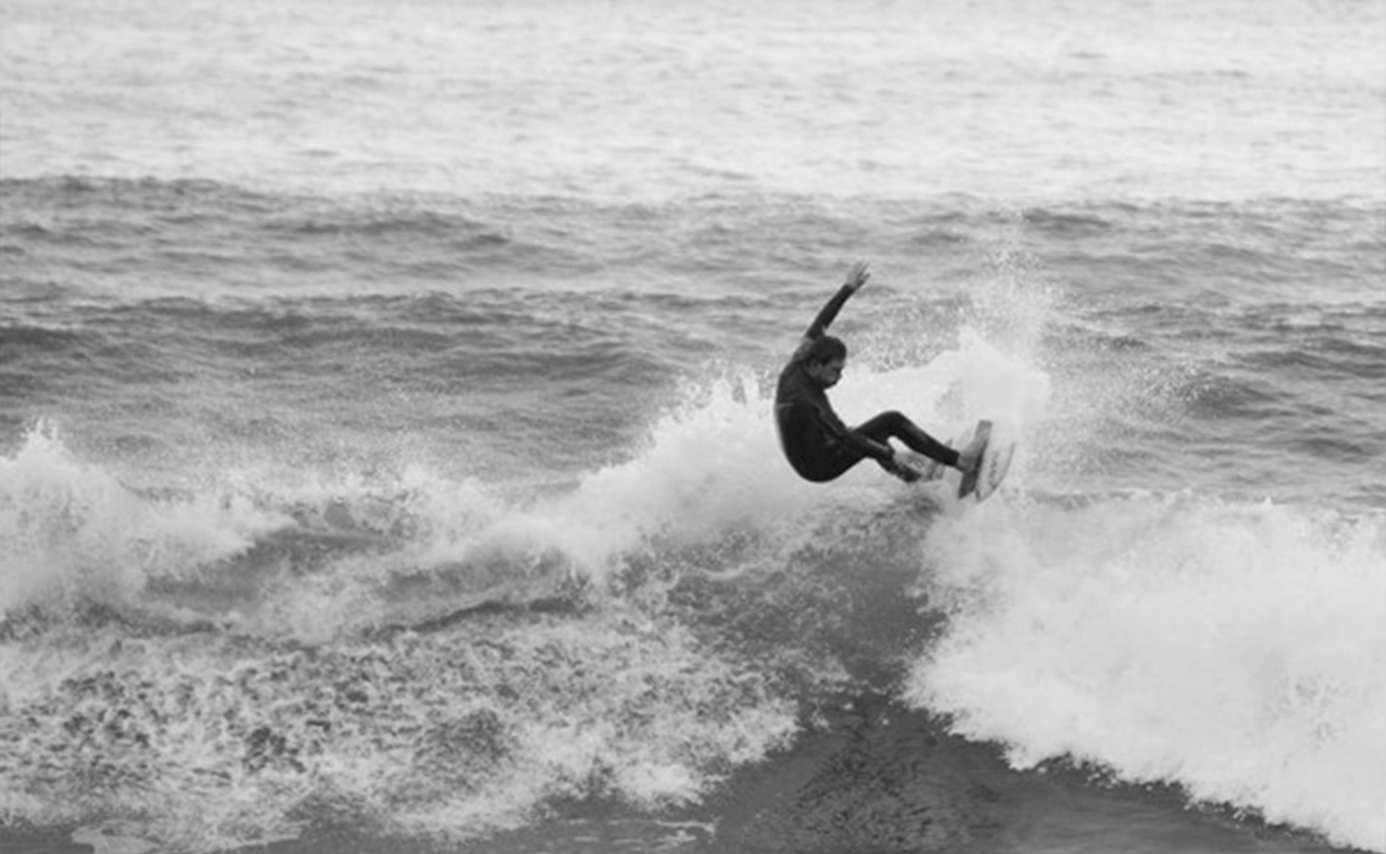 Photo en noir et blanc d'un rider décollant de la lèvre d'une vague déferlante
