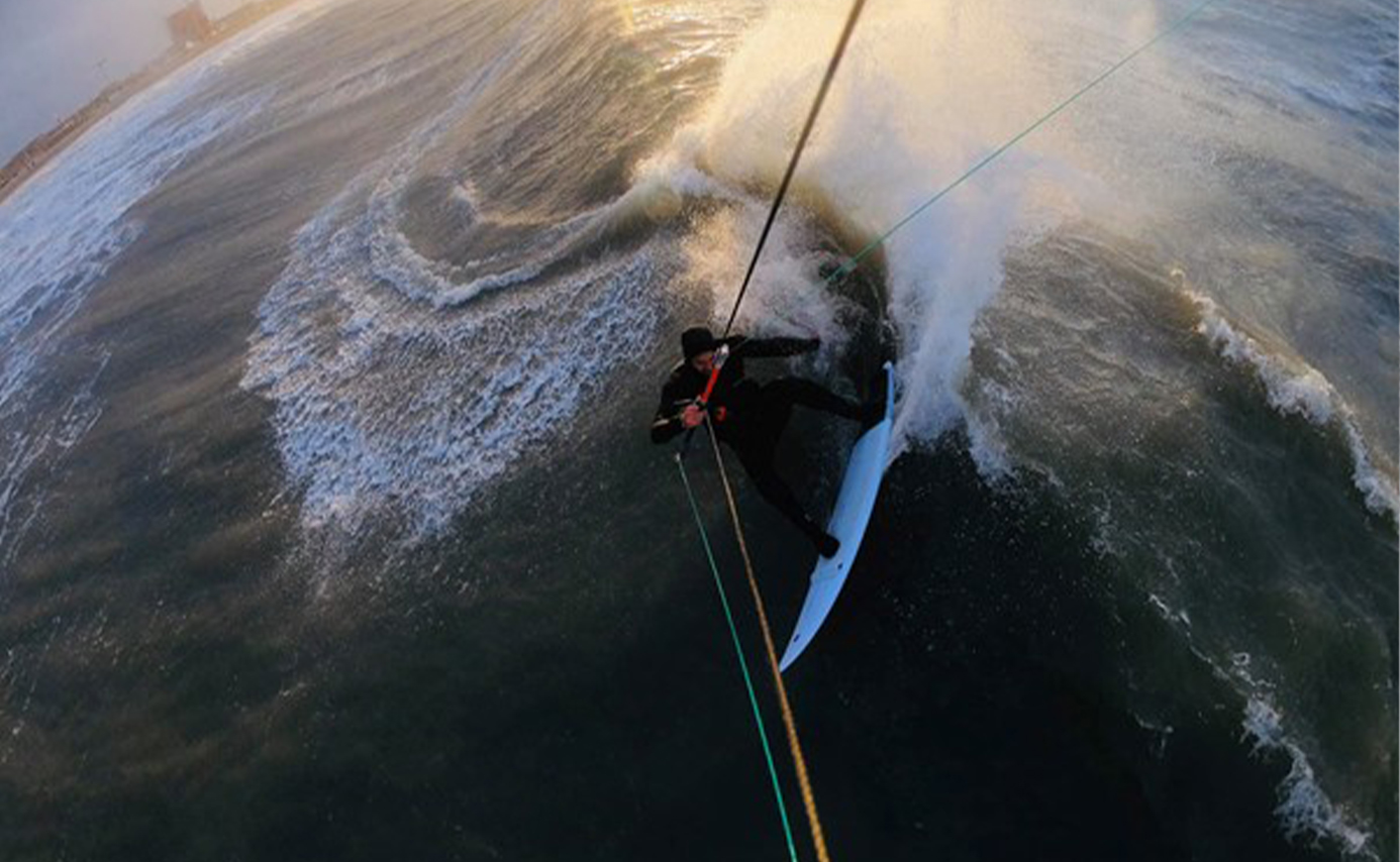Un kitesurfeur engagé au fond d'un tube, lignes de kite tendues